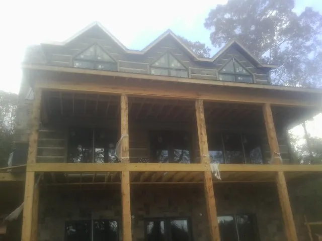 Dormers and porch framing on a large log home under construction — Roof Coating work by our crew in Elgin